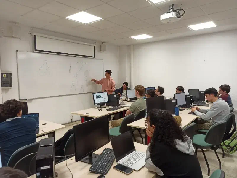 A weekly club session: a speaker at the whiteboard and students at their computers
